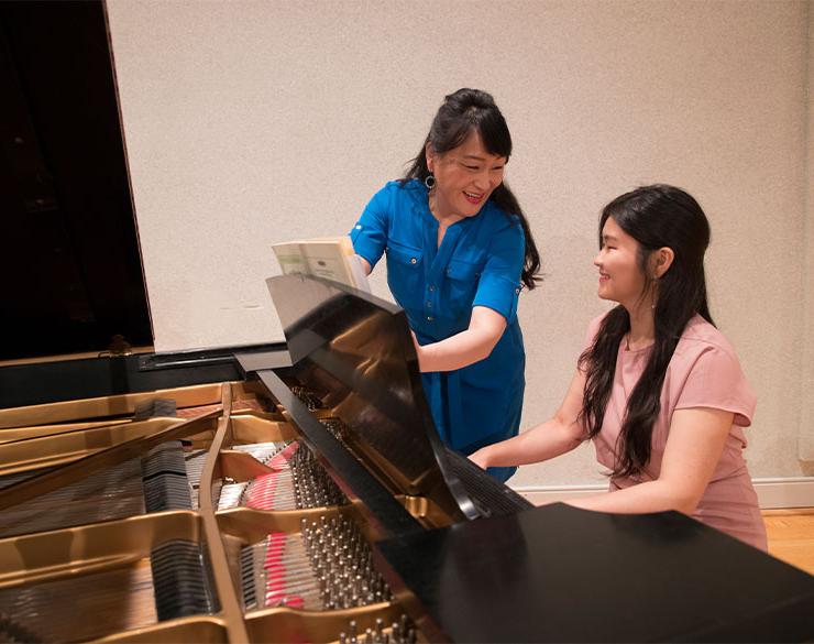 Professor helps student with piano performance